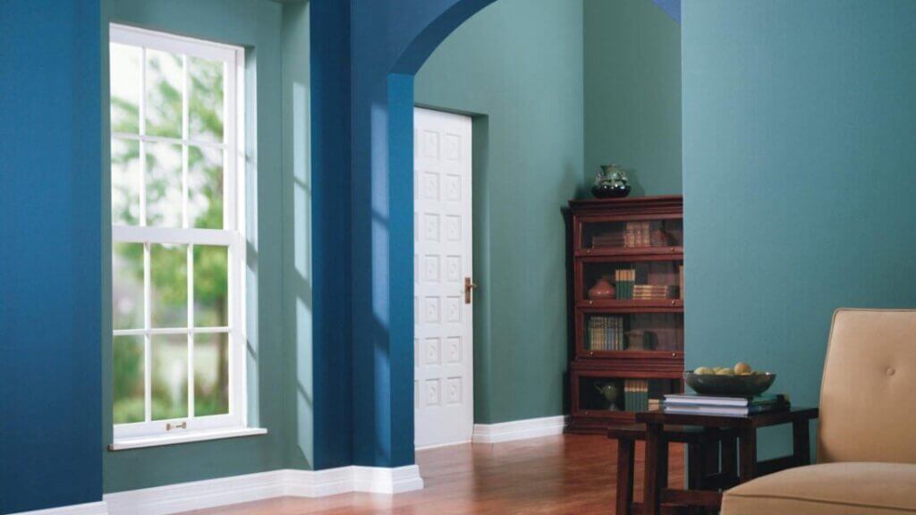 Room with blue and green walls, a table and chair also a bookcase